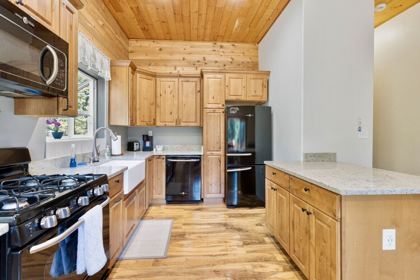 Una cocina con armarios de madera, un refrigerador de acero inoxidable y una estufa a gas.