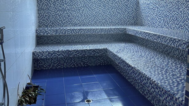 A corner jacuzzi with mosaic tiles, a window, and a blue floor. - Charming 3-bedroom apartment in vibrant Gaira perfect for relaxing (Gaira)