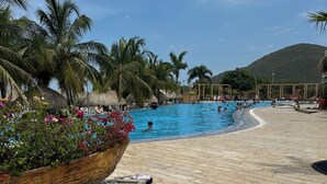 A swimming pool with palm trees and a mountain in the background. - Charming 3-bedroom apartment in vibrant Gaira perfect for relaxing (Gaira)