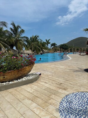 A swimming pool with palm trees and a mountain in the background. - Charming 3-bedroom apartment in vibrant Gaira perfect for relaxing (Gaira)