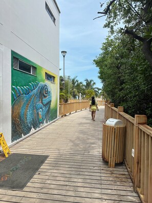Une promenade en bois mène à un bâtiment orné d’une fresque représentant une créature marine.