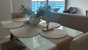 A dining area with a glass table, woven placemats, and a decorative seahorse centerpiece. - Charming 3-bedroom apartment in vibrant Gaira perfect for relaxing (Gaira)