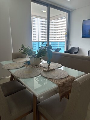 A dining area with a glass table, woven placemats, and a decorative seahorse centerpiece. - Charming 3-bedroom apartment in vibrant Gaira perfect for relaxing (Gaira)