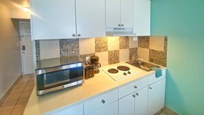 A compact kitchen with white cabinets, a microwave, a coffee maker, and a stove. - NEW Amazing Ocean View Getaway Studio in Daytona (Daytona Beach)