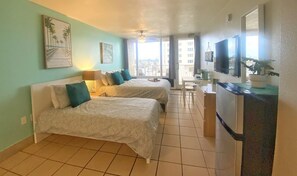 Habitación de hotel con dos camas, kitchenette y balcón con vistas.