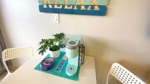 A table with a teal placemat, a plant, a coffee maker, and a sign that reads "RELAX". - NEW Amazing Ocean View Getaway Studio in Daytona (Daytona Beach)