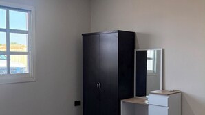 Un dormitorio con cama, armario, escritorio y espejo.