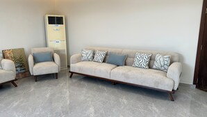 Un salón con un sofá color beige, dos sillones y cojines estampados.