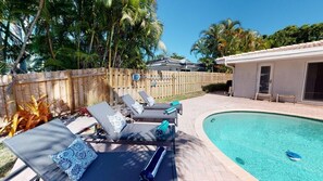 A swimming pool area with lounge chairs and a wooden fence. - Villa by the Sea (Fort Lauderdale)