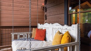 A wooden swing bed with a white headboard, a knitted blanket, and several pillows in various colors. - Its Got It All Yall by Avantstay Sleeps 27 Indoor Pool + Hot Tub + Theater + Near Pigeon Forge (Pigeon Forge)