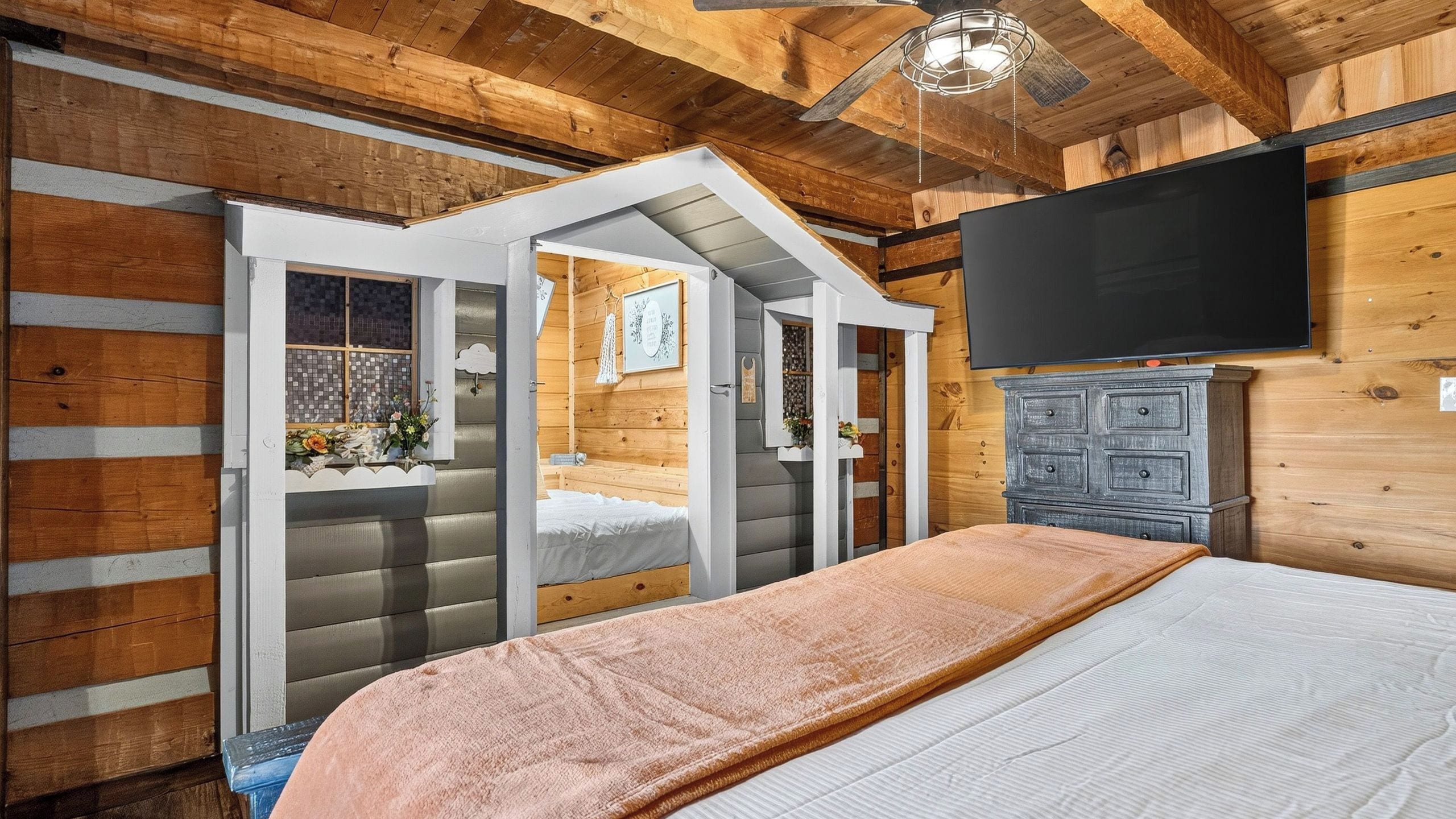 A bedroom with a bed, a TV, and a wooden wardrobe.