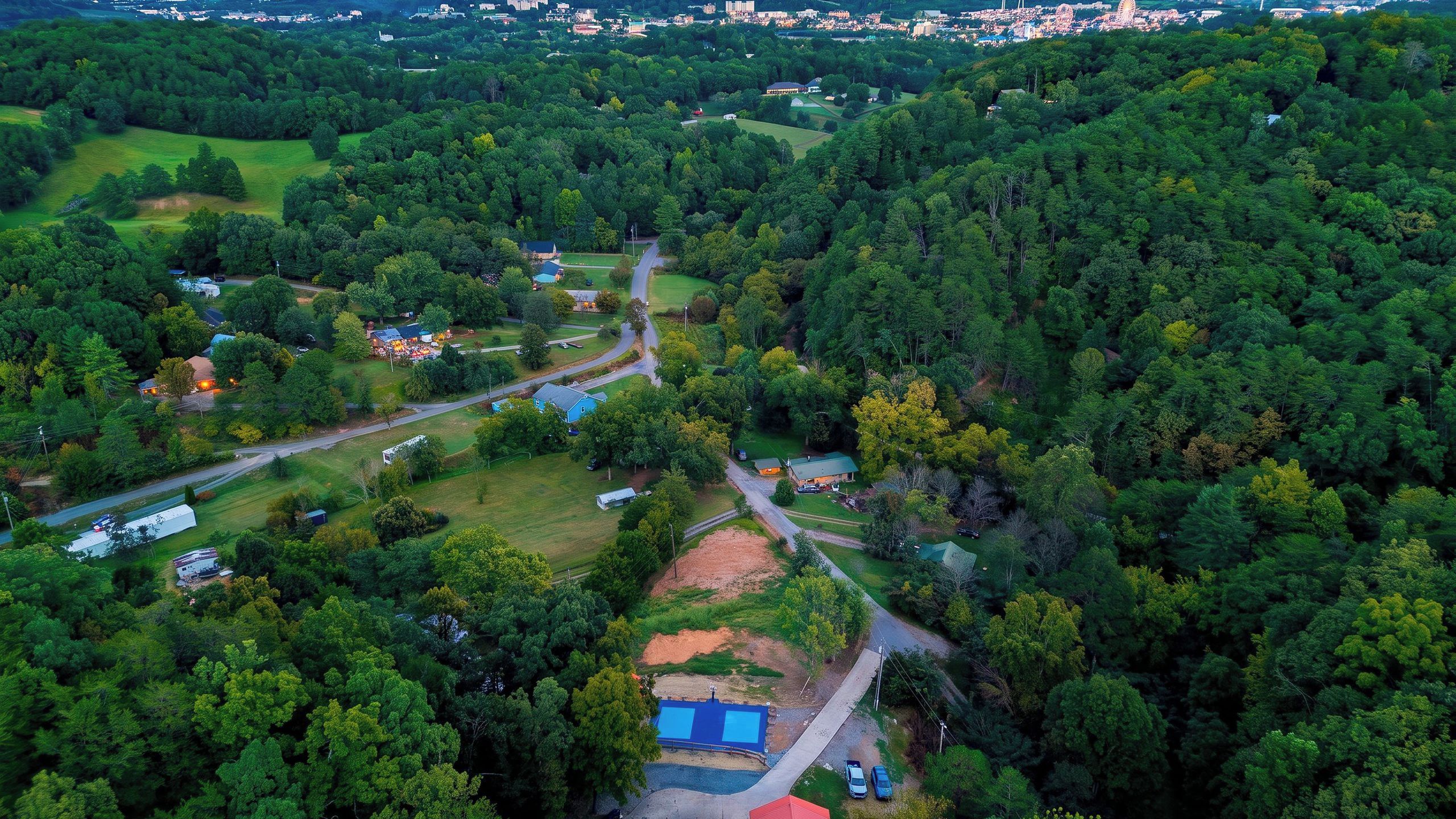 An aerial view of a residential area with houses, roads, and a large green park.