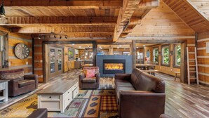 A log cabin interior with a fireplace, leather furniture, and a wooden floor. - Its Got It All Yall by Avantstay Sleeps 27 Indoor Pool + Hot Tub + Theater + Near Pigeon Forge (Pigeon Forge)