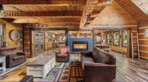 A log cabin interior with a fireplace, leather furniture, and a wooden floor. - Its Got It All Yall by Avantstay Sleeps 27 Indoor Pool + Hot Tub + Theater + Near Pigeon Forge (Pigeon Forge)