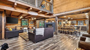 A spacious living area with a fireplace, a dining table with chairs, and a kitchen visible through an open door. - Its Got It All Yall by Avantstay Sleeps 27 Indoor Pool + Hot Tub + Theater + Near Pigeon Forge (Pigeon Forge)