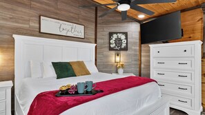 A neatly arranged bedroom with a bed, bedside tables, a dresser, a wall-mounted TV, and a ceiling fan. - Its Got It All Yall by Avantstay Sleeps 27 Indoor Pool + Hot Tub + Theater + Near Pigeon Forge (Pigeon Forge)