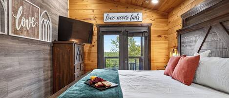 Een slaapkamer in een houten hut met een bed, een ontbijttafel en een bord waarop staat 'liefde faalt nooit'.
