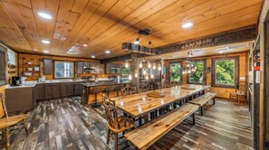 A rustic cabin-style kitchen with wooden floors, a central island, and a dining area with benches. - Its Got It All Yall by Avantstay Sleeps 27 Indoor Pool + Hot Tub + Theater + Near Pigeon Forge (Pigeon Forge)