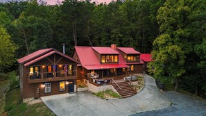A two-story log cabin with a red roof, multiple windows, and a stone foundation. - Its Got It All Yall by Avantstay Sleeps 27 Indoor Pool + Hot Tub + Theater + Near Pigeon Forge (Pigeon Forge)