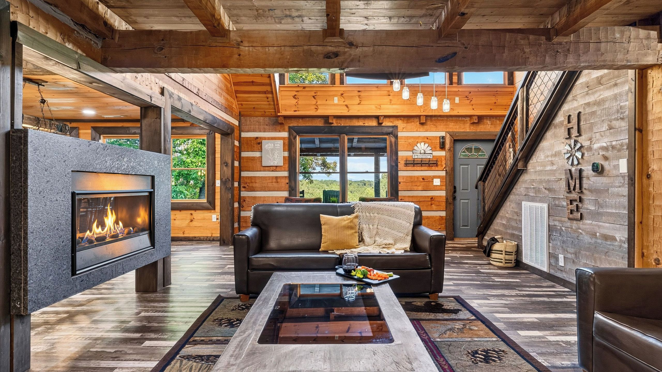 A cozy living room with a fireplace, a leather sofa, and a coffee table with a tray of snacks.