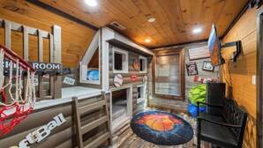 A basketball-themed room with a hoop, a bench, and a wall with sports memorabilia. - Its Got It All Yall by Avantstay Sleeps 27 Indoor Pool + Hot Tub + Theater + Near Pigeon Forge (Pigeon Forge)