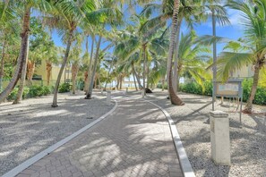 A paved pathway lined with palm trees and a building in the background. - Villa Terra Mar (Lauderdale-by-the-Sea)