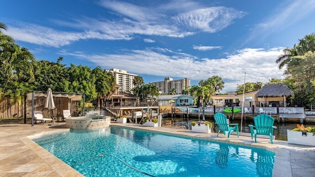 A swimming pool with lounge chairs, a dock, and a thatched-roof structure. - Waters Edge (Lauderdale-by-the-Sea)