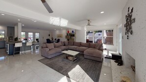 A spacious living area with a large L-shaped sectional sofa, a coffee table, and a kitchen in the background. - Waters Edge (Lauderdale-by-the-Sea)