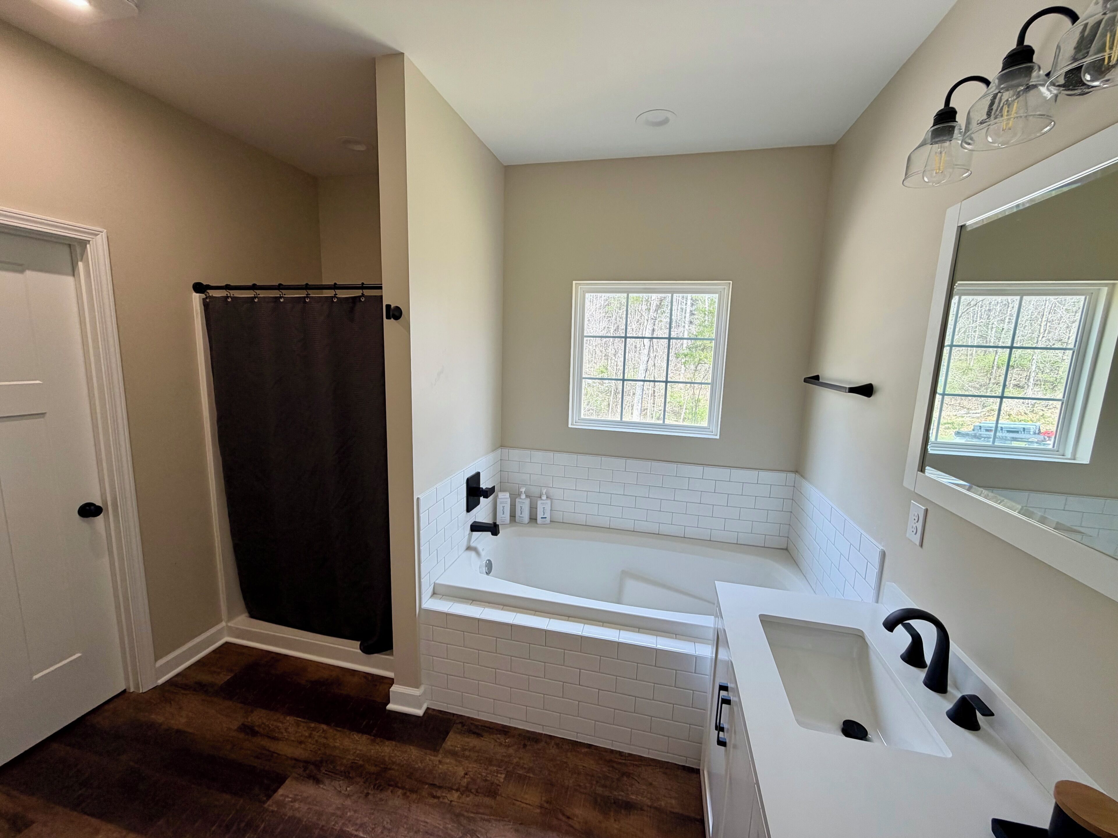 Une salle de bain avec une baignoire, un lavabo, une fenêtre et un rideau de douche.