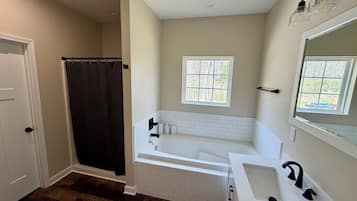 Une salle de bain avec une baignoire, un lavabo, une fenêtre et un rideau de douche.