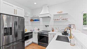 Una cocina moderna con electrodomésticos de acero inoxidable, armarios blancos y una isla central con fregadero.