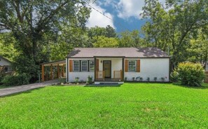 A single-story house with a front porch, a small front yard, and a garage. - Luxe Latitude Modern Luxury Staycation Retreat (Atlanta)