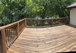 A wooden deck with a curved railing, surrounded by dense foliage. - Luxe Latitude Modern Luxury Staycation Retreat (Atlanta)
