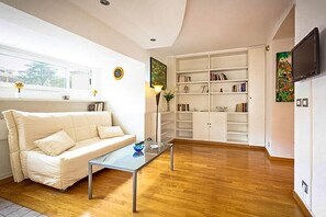 A living room with a sofa, a glass coffee table, a bookshelf, and a TV mounted on the wall. - Next to the Olympic Stadium and the Milvio Bridge (Roma)