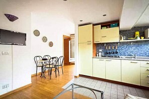 A kitchen with wooden flooring, a dining table with chairs, and light-colored cabinets. - Next to the Olympic Stadium and the Milvio Bridge (Roma)