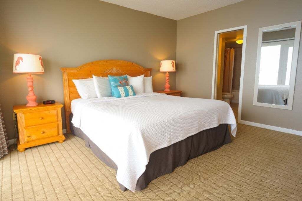 A hotel room with a large bed, two bedside tables, a nightstand, and a mirror on the wall.