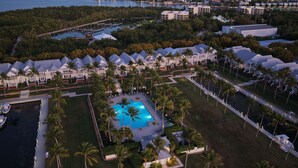 Ein Luftbild eines Resorts mit mehreren bungalowsartigen Unterkünften, einem zentralen Swimmingpool und umliegender Bepflanzung.