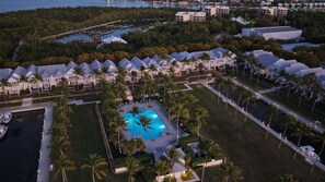 Ein Luftbild eines Resorts mit mehreren bungalowsartigen Unterkünften, einem zentralen Swimmingpool und umliegender Bepflanzung.