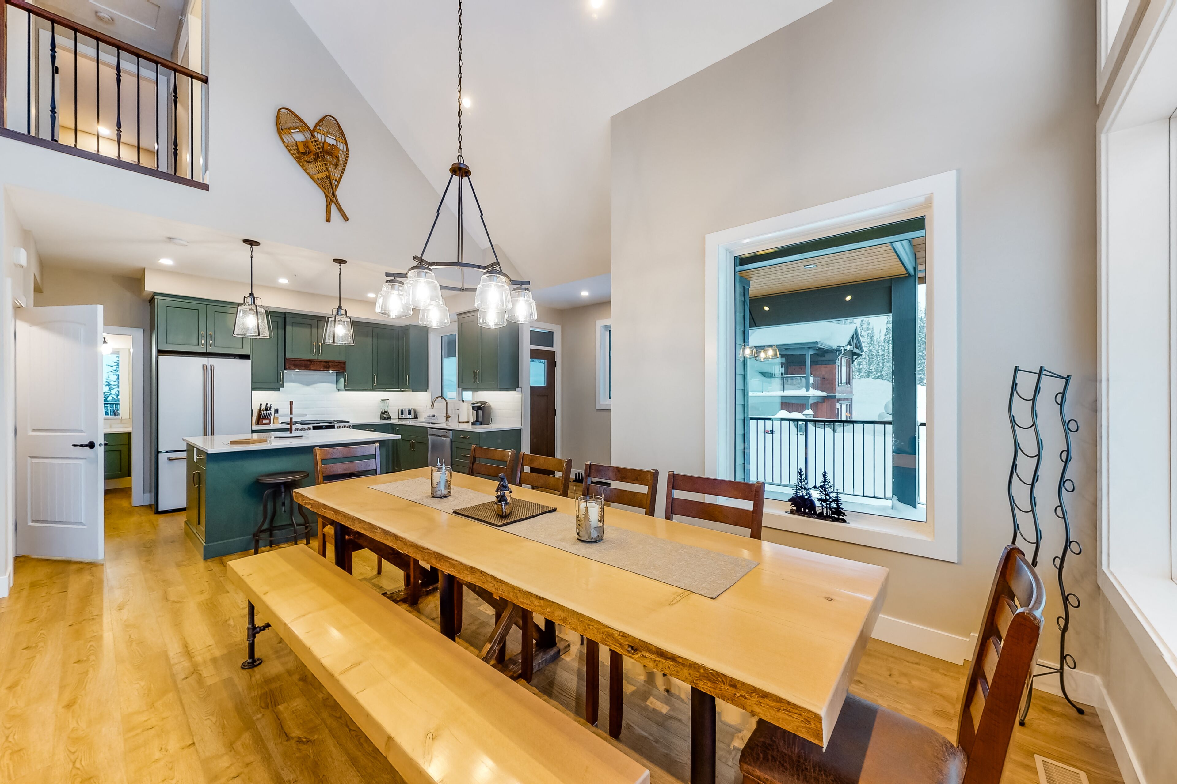 A spacious kitchen with a central island, wooden dining table, and bench seating.