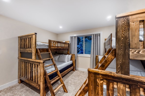 Una habitación con literas, una escalera, una ventana con cortinas y un espejo.