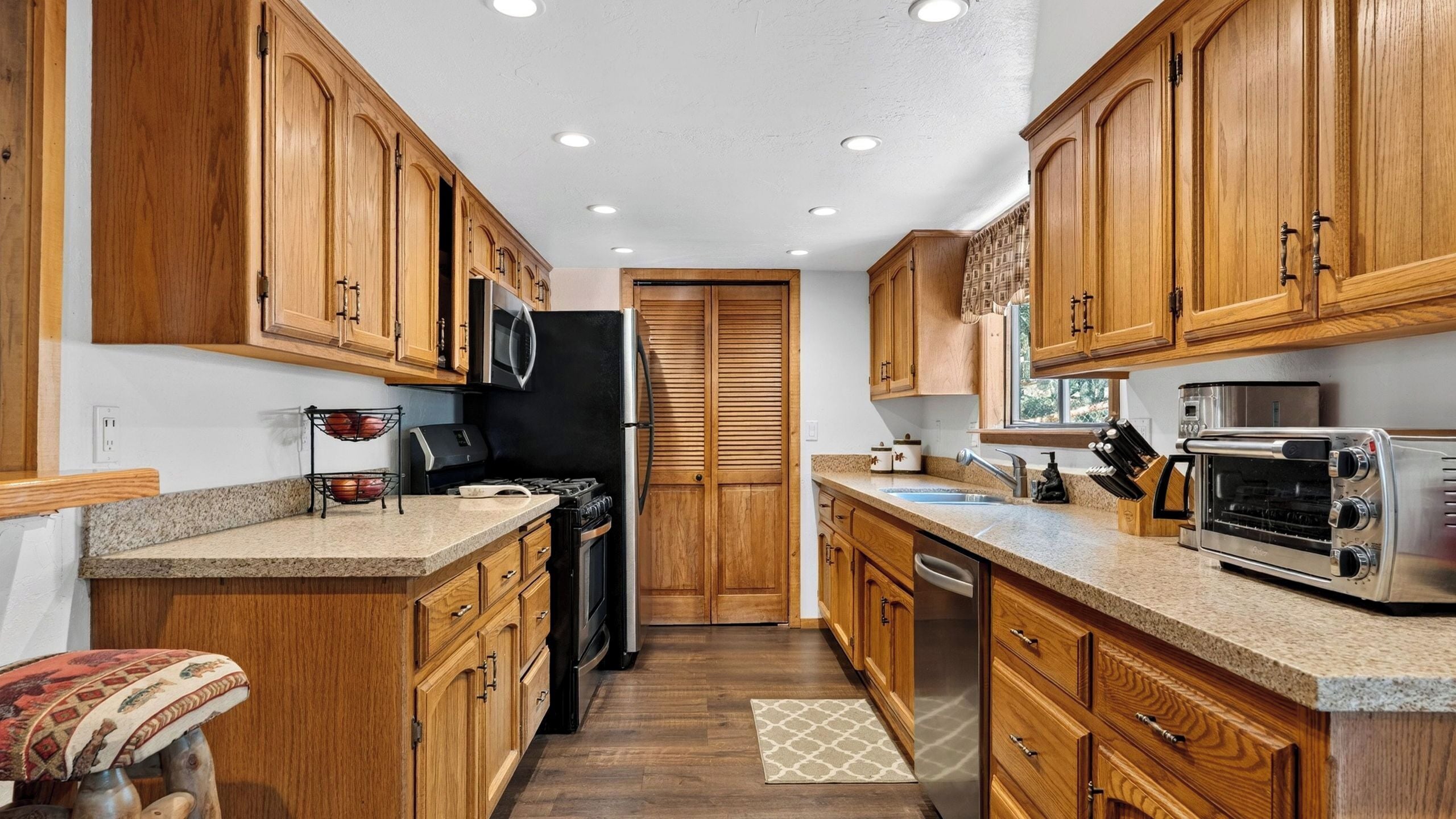 A compact kitchen with wooden cabinets, a black refrigerator, a microwave, a toaster, and a dishwasher.