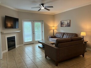 A living room with a fireplace, a sofa, a coffee table, a TV, and a ceiling fan. - Sweet Retreat - Unit 5206 - FREE Attraction Ticket with EACH night Stay Including Dollywood (Pigeon Forge)