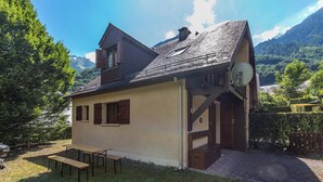 Une maison avec un toit en pente, une antenne parabolique, un banc en bois et une vue sur un paysage montagneux.