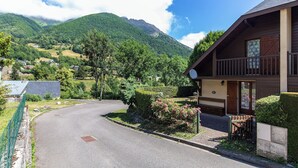 A mountain-view property with a curved driveway, wooden exterior, and a satellite dish.