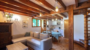 A cozy living room with a sectional sofa, a small table, and a kitchen in the background.