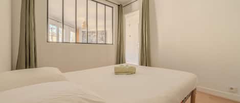 A bedroom with a large window, a bed, and a view of the cityscape.