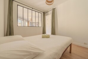 A bedroom with a large window, a bed, and a view of the cityscape. - Le Versaillais - Petfriendly - Wifi (Versailles)