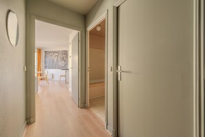 A hallway with a door leading to a room, a mirror, and a view of a dining area. - Le Versaillais - Petfriendly - Wifi (Versailles)