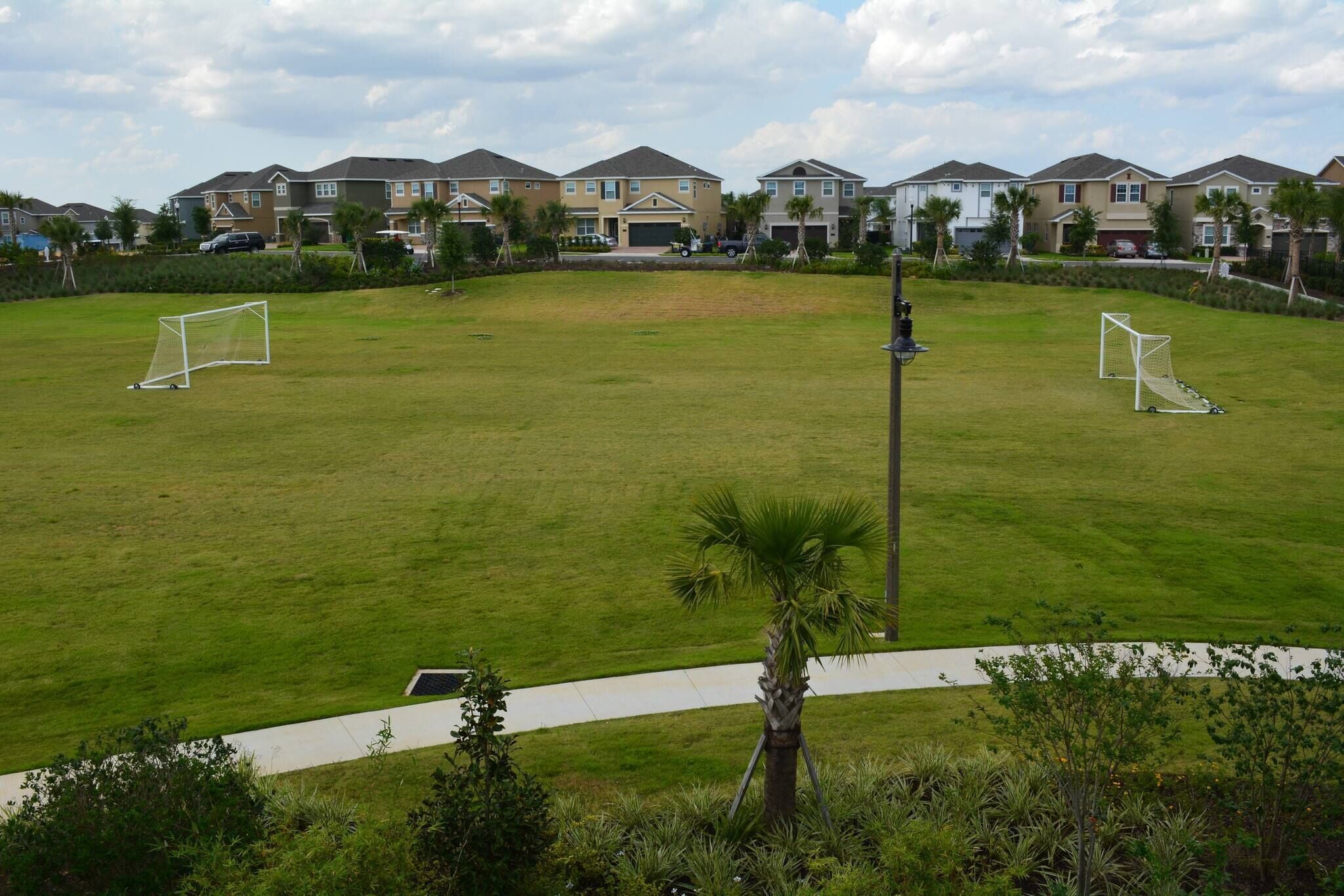 A residential area with houses, a soccer field, and a pathway.