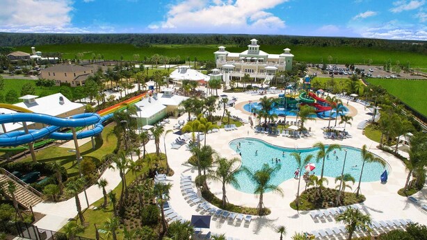 A resort with a large pool, water slides, and a central building. - Disney Dreams Luxury Home With Private Water Park (Kissimmee)